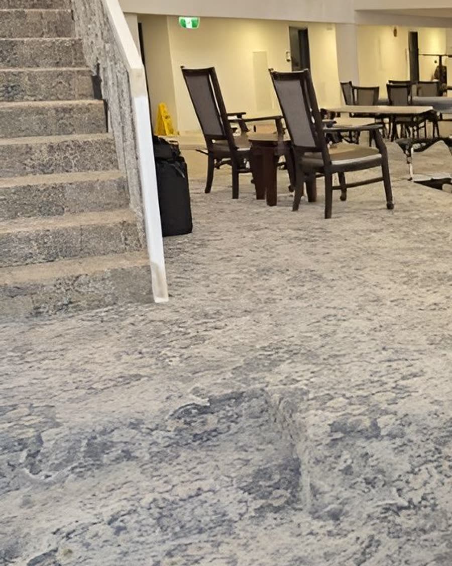 Patterned broadloom carpet in a commercial lobby beside a stone staircase.