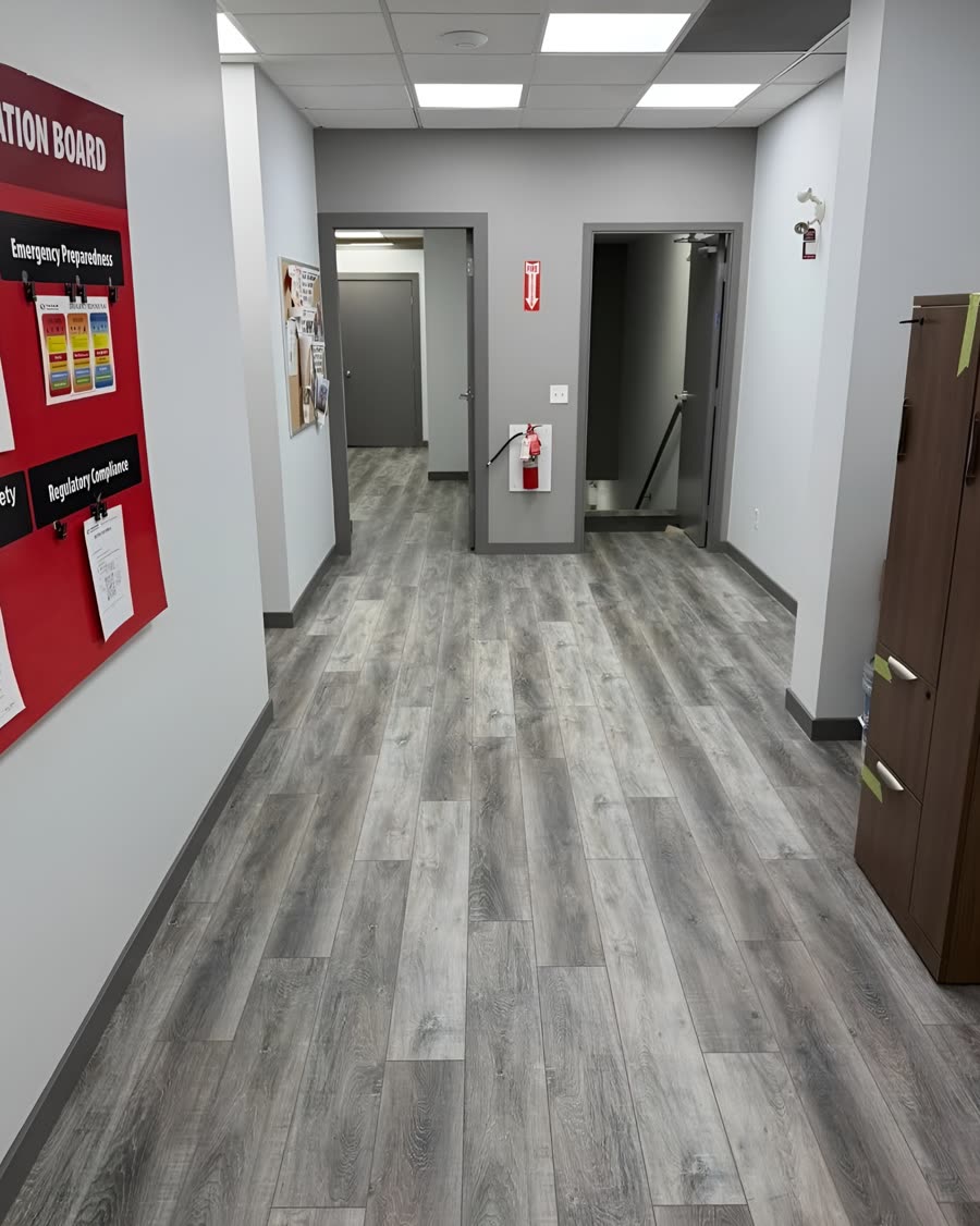 Grey wood look click plank vinyl running down an office corridor.