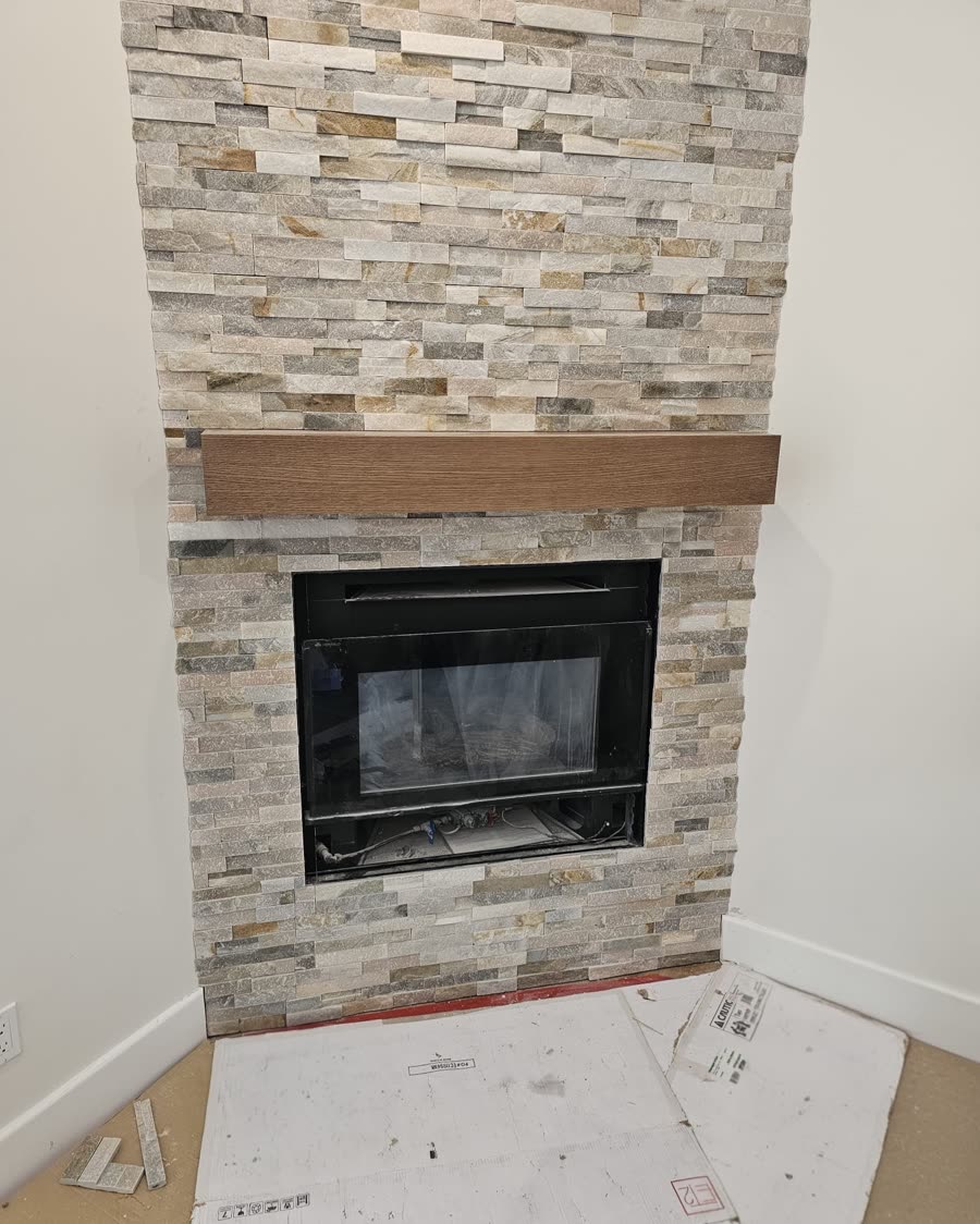 A brick and stone fireplace surround finished with a solid wood mantel.